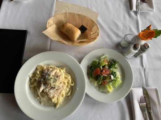 Fettuccine with chicken Alfredo, a house salad and complimentary bread are some of the food items offered at Milano Ristorante. (Megan Cardona/Community Impact Newspaper)