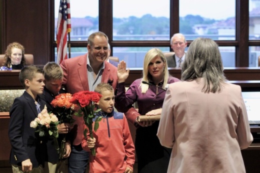 Callie Rigney raises her hand to take the oath of office, next to her husband and sons