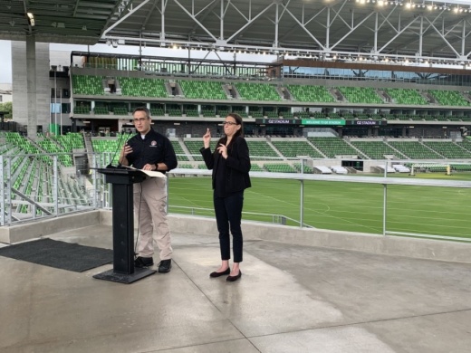 Photo of a man speaking and woman doing ASL interpretation at Q2 stadium