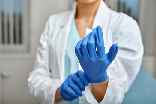 doctor fits latex glove onto hand