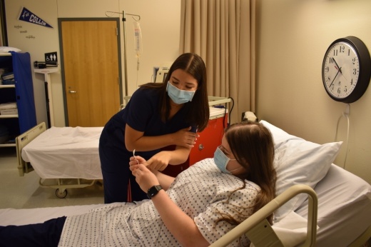 Frisco ISD senior Isabella Scuilla (left) practices her health care skills on fellow student Madelaine Ross. (Courtesy Frisco ISD)