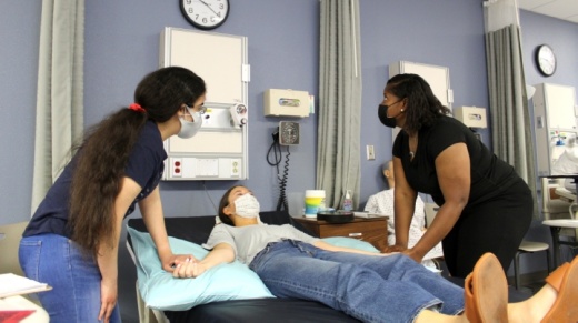 two students and an instructor demonstrate nursing skills