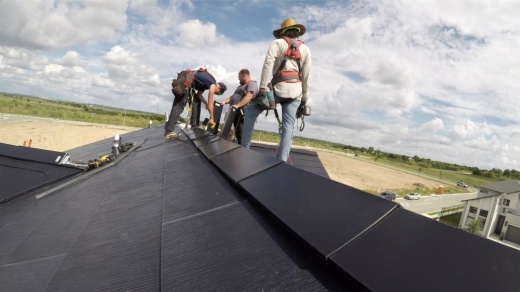 Photo of workers on a roof installing solar panels