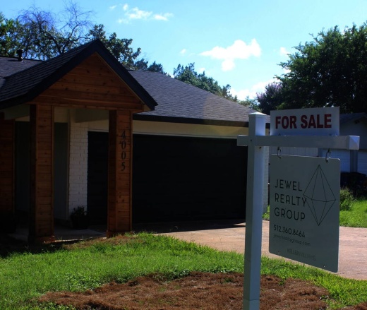 Photo of a house with a "for sale" sign in the front yard