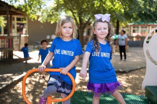 Photo of two girls on a playground with "Live United" shirts