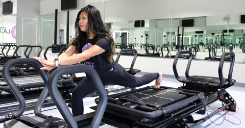 To-ong performs a lunge with resistance on the lagree machine. To-ong said she teaches clients how to do slow, controlled exercises so they leave the session feeling sore and accomplished. (Ally Bolender/Community Impact Newspaper)