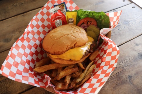 The cheeseburger and fries combo ($11) is served with lettuce, tomato, onion, pickles and condiments on the side. (Photos By Zara Flores/Community Impact Newspaper)