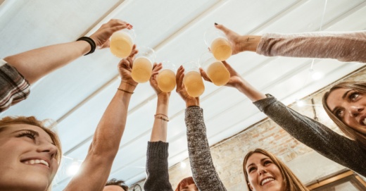 group of peope holding up beers