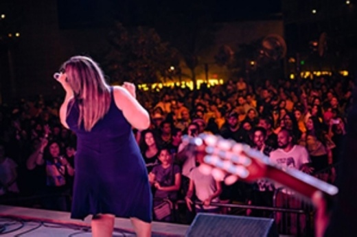 lady on stage singing in front of huge crowd at music in the park in pflugerville texas