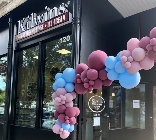 a storefront is decorated with multi-colored balloons