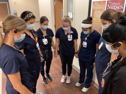Photo of nurses holding hands with bowed heads