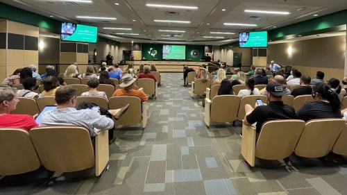 A group of people attend a Carroll ISD school board meeting
