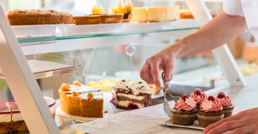 bakery baker serving red velvet cupcakes and a front case with carrot cakes and pies