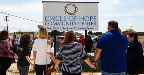People join hands around the Circle of Hope Community Center sign. (Courtesy Circle of Hope Community Center)