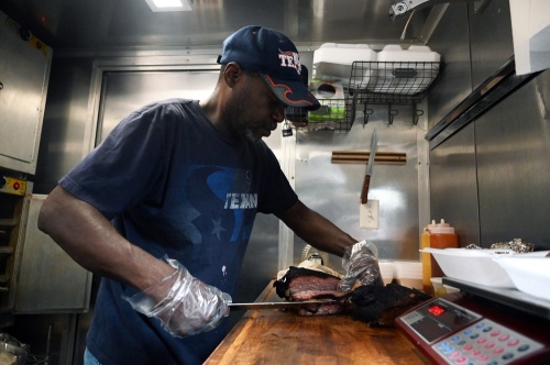 Pitmaster Orie King serves up a brisket platter at OG’s Barbeque at the Cedar Pork food truck park. (Leila Saidane/Community Impact Newspaper)