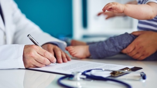 doctor writing notes with mother and baby