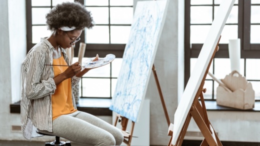 Black artist sitting in chair while mixing color palette