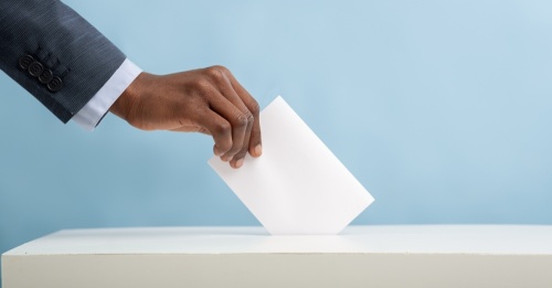 Man placing an envelop in the ballot box