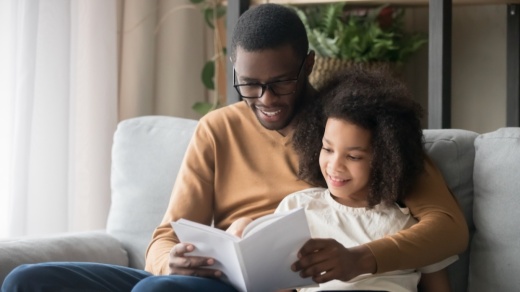 Black father and daughter reading a book