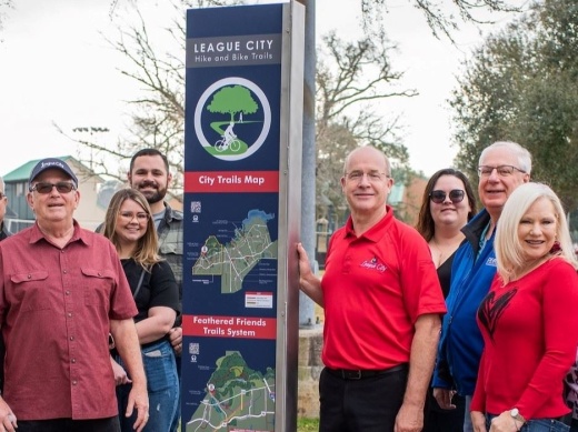 City Manager John Baumgartner (holding the sign) stands with other stakeholders near one of the new trailhead signs installed across Lynn Gripon Park at Countryside and Rustic Oaks Park. (Courtesy city of League City)