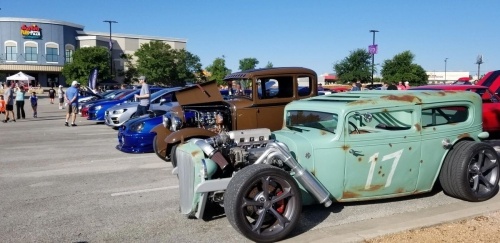 vintage cars lined up in a parking lot on a sunny day