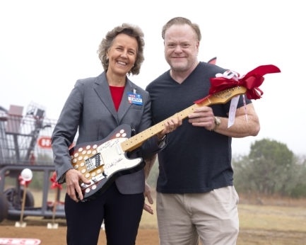 Cathy Harm, H-E-B Group vice president Central Texas, and Mike Farr, the owner of Nutty Brown, hold a signed guitar that will be displayed in the new H-E-B. (Courtesy H-E-B)
