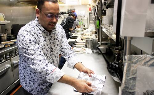 AJ Jain, an owner of Delhi6 Indian Kitchen, puts together to-go orders on March 2. (Samantha Douty/ Community Impact Newspaper)