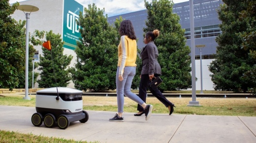 two people walking next to robot