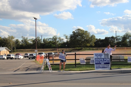 Amy Jimenez and Cordell Bunch waved at cars near the polling location at the Knights of Columbus Hall, Tuesday, Nov. 2 supporting the 2021 NBISD bond election. (Eric Weilbacher/Community Impact Newspaper)