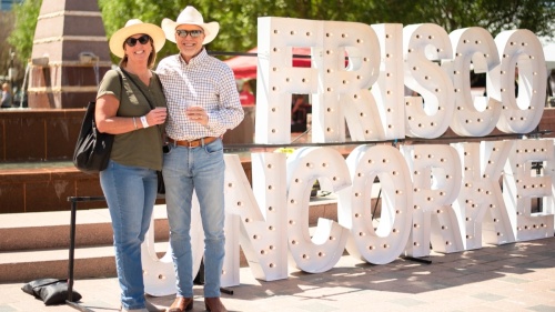 couple smiling in front of Frisco Uncorked sign