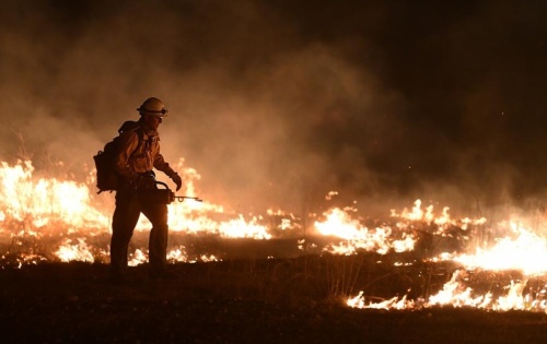 Francisco Lugo, Texas State Forrest Service Fredricksburg Task Force strike team firefighter, walks a controlled "burn-out" that was started to manage a large fire April 9, 2022, at Joint Base San Antonio-Camp Bullis. Bexar County officials have declared an emergency and plan to ban outdoor burning in response to conditions they say heighten the risks of similar wildfires. (Courtesy U.S. Air Force/Brian Boisvert)