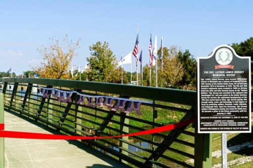 A ribbon is stretched across a bridge where a monument sign is located.