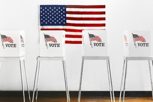 Voter booths in front of an American flag.