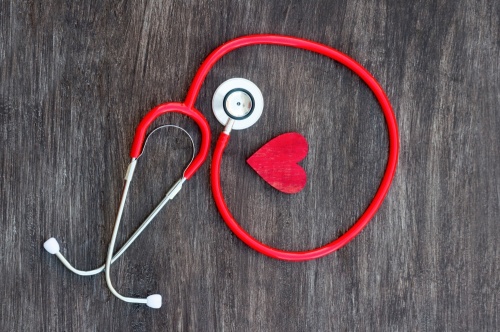 Stethoscope and red heart on wooden background