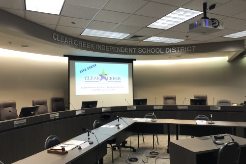 The Clear Creek ISD board room with two tables, chairs and a projector.