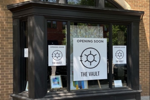 A storefront with a sign that reads Coming Soon The Vault