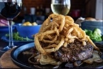 A plate with two steaks and grilled and fried onions
