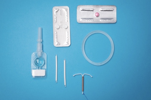 A photo of contraceptive methods and reproductive tools on a blue table.