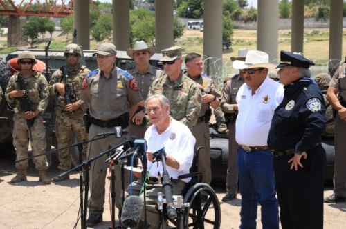 Texas Gov. Greg Abbott speaks at a news conference in Eagle Pass, Texas. State and local officials stand behind him.