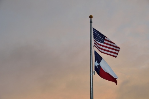Photo of an American flag and a Texas flag flying on the same flagpole