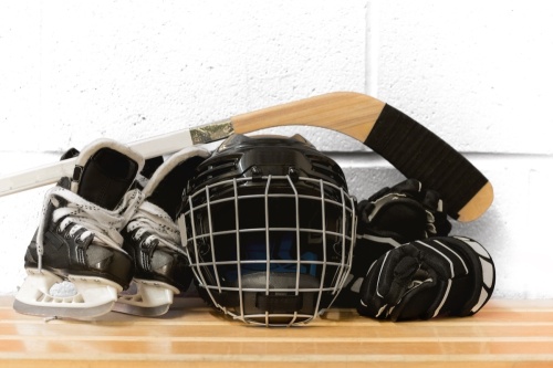 a pair of hockey skates, helmet, safety pads, and hockey stick 