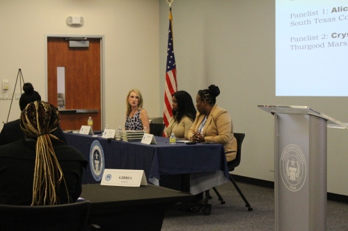 Woman speaks during panel session alongside other panel members.