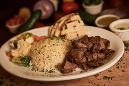 a plate with rice, beef, vegetables and pita bread