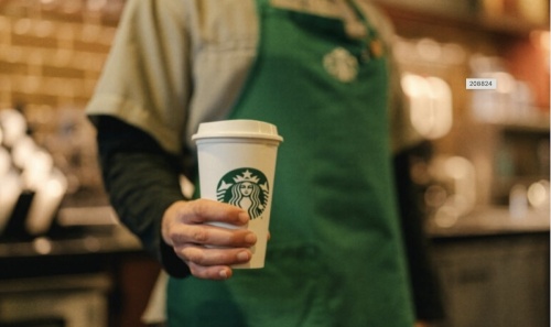 a Starbucks employee holding a cup