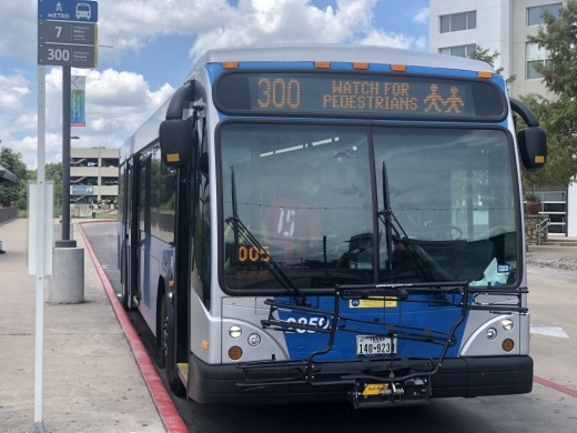A large metro bus is parked at a bus stop.