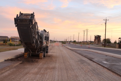 paving equipment and a scraped portion of Klein Road in New Braunfels that is being repaved