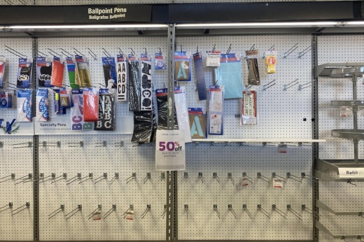 A shelf at staples that is mostly bare and has a 50% off sign. 