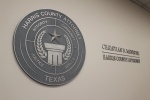 Gray seal of county attorney with a star over a column, along with the attorney's name. 