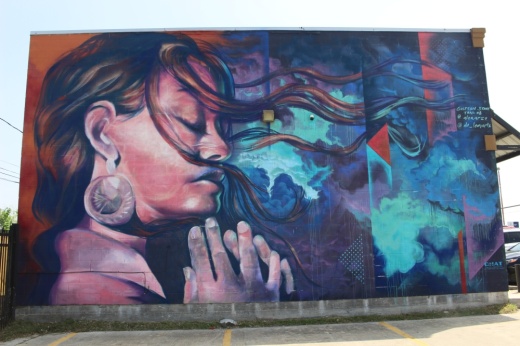 A mural in the Gulfton community in Houston depicts a woman in a meditative state facing a swirl of blue colors. (Shawn Arrajj/Community Impact Newspaper)