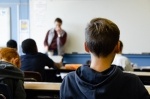 A male student looks forward in a classroom.